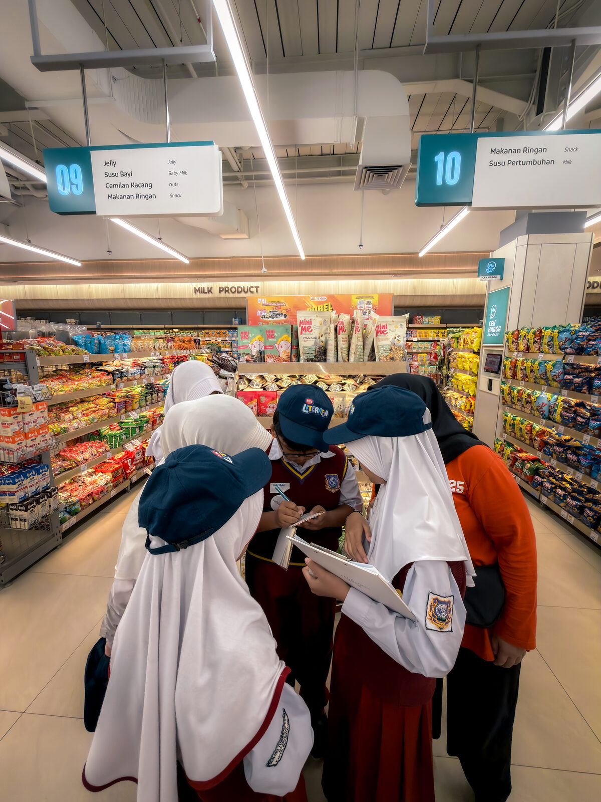 Siswa mencatat daftar belanja di lorong supermarket